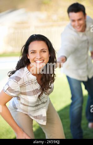 Come with me. A young woman playfully pulling her husband towards her. Stock Photo