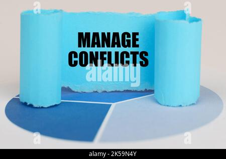 Business concept. On the blue diagram is a twisted paper sign with the inscription - MANAGE CONFLICTS Stock Photo
