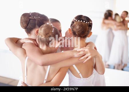 Getting ready for the performance. a group af young ballerinas huddling together in the studio and laughing. Stock Photo