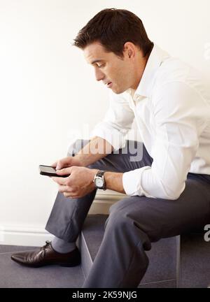 Checking the latest stock market news via mobile. A handsome young businessman using his cellphone. Stock Photo