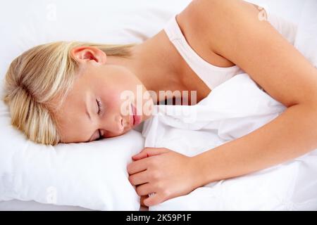 Getting in her 8 hours. Young woman peacefully sleeping comfortably on white linen. Stock Photo