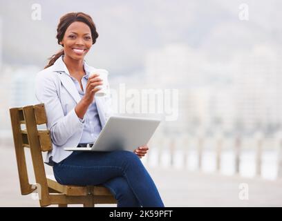 Getting out of the office. A pretty young woman working on her laptop on the promenade. Stock Photo