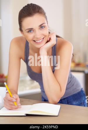 Shes a writer by heart. Portrait of an attractive young woman writing in her diary. Stock Photo