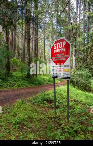 No Dumping warning sign to polluters beside hiking trail in lush green forest at Hemer Provincial Park near Nanaimo, British Columbia. Stock Photo