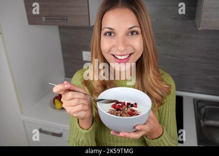 https://l450v.alamy.com/450v/2k59tmg/teenage-girl-eating-muesli-granola-oatmeal-with-dried-fruits-and-yogurt-looking-at-camera-in-kitchen-2k59tmg.jpg