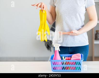 Cleaning protection tools. Housework equipment. Advertising product. Unrecognizable woman holding yellow gloves pointing gesture basket with cleaner m Stock Photo