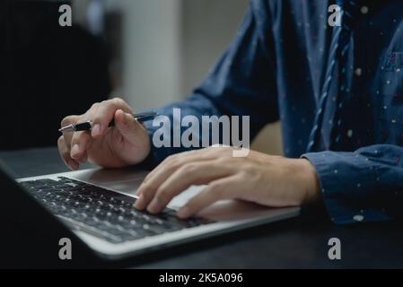 Man using computer laptop working internet searching social media and communications digital technology online at desk. Stock Photo
