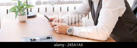 Happy businessman at his desk in office talking on phone. A young businessman is sitting in the office in business clothes, a successful bearded caucasian guy Stock Photo