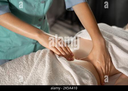 Hands massaging belly in the spa. Relaxing massage and body shaping massage, lymphatic drainage, manual and aesthetic procedures Stock Photo