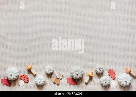 Autumn creative craft background with decorative clay pumpkins and wooden autumn leaves. Decorative pumpkins flat lay on natural fabric background Stock Photo