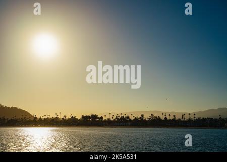 Perfect golden blue Santa Barbara beach with palm trees silhouettes against hills and ocean. Holiday bliss in tropical locations Nature travel landsca Stock Photo