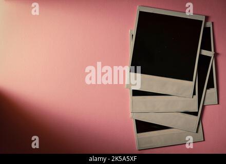 Stack of vintage photos. Blank photo frame on rose background. Stock Photo