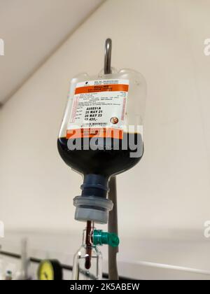 Close up of IV plastic bag with drip chamber in recovery room at intensive care unit of hospital with bokeh background. No people. Stock Photo