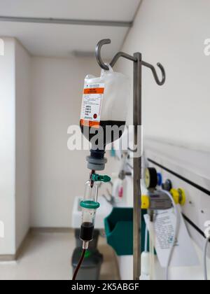 Close up of IV plastic bag with drip chamber in recovery room at intensive care unit of hospital with bokeh background. No people. Stock Photo