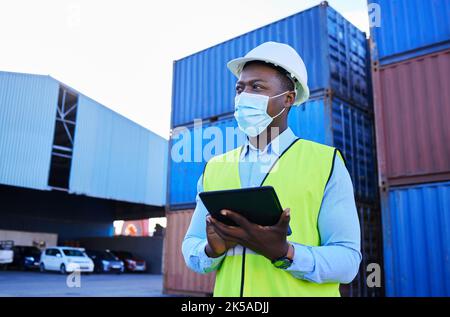 Man, logistics worker, and covid with a tablet to check inventory in mask with cargo container in background. Black industry employee working Stock Photo