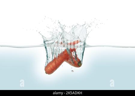 Two carrots splashing in water. Side view on white background. Stock Photo