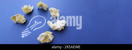 Lot of crumpled papers lying on drawn light bulb closeup Stock Photo