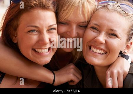 Friends having fun. Portrait of three smiling best friends embracing. Stock Photo