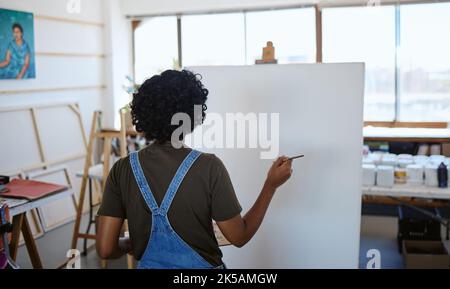 Art, paint and creative woman painting on canvas with inspiration in a workshop studio from behind. Back of an artist, designer or painter learning Stock Photo