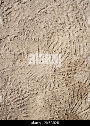 Beige textured wall with plaster applied with putty knife in irregular dashes and strokes. Vertical Stock Photo