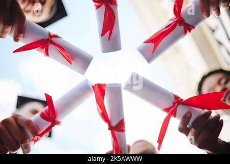 Graduation circle, success and students certificate, diploma or degree in hands huddle from below. Low angle, education and university people, friends Stock Photo