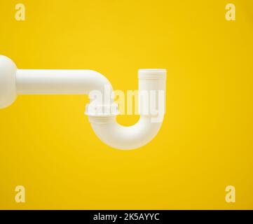 A closeup of a white siphon pipe on a vibrant yellow background with copy space Stock Photo