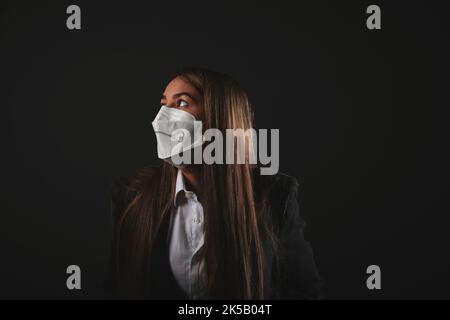 Executive young woman wearing medical mask with drawn smile on black background Stock Photo