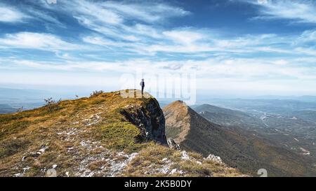 A lone hiker standing on top of a green mountain Stock Photo
