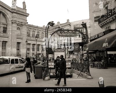 A grayscale shot of people standing in front of the Paris Metro exit near Gare du Nord Stock Photo