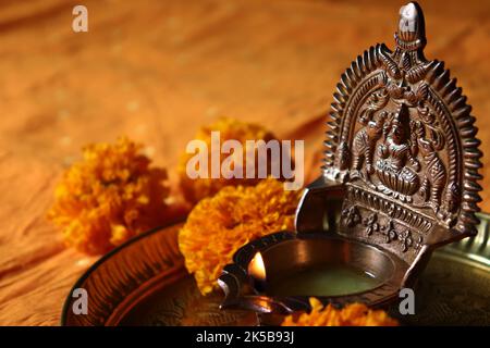 Lit oil brass Goddess Lakshmi /Gajalakshmi vilakku in a copper plate with marigold flowers/Diwali/Deepavali festival Stock Photo