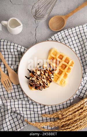 Croffles with almonds chocolate sauce topping and caramel on plate, top view on white background isolated clipping path Stock Photo