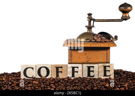 Old manual coffee grinder with roasted coffee beans and the text Coffee made of wooden blocks, isolated on white background, photography. Stock Photo