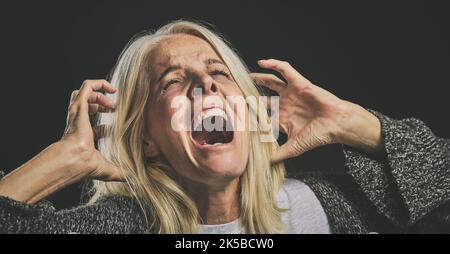 Screaming senior woman, mental health and depression from bipolar anxiety, stress and scary fear on black background. Schizophrenia, psychology and Stock Photo