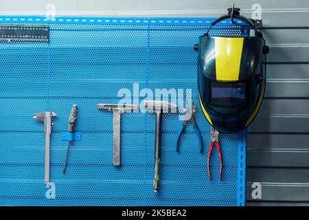welding mask hanging on a stand with tools Stock Photo