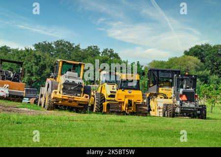 A view of tractors parked on the grass field under the blue sky in the countryside Stock Photo