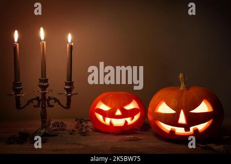 Halloween pumpkin head jack-o-lantern on wooden background. Spooky halloween pumpkins, Jack O Lantern, with an evil face and eyes and old candles with Stock Photo