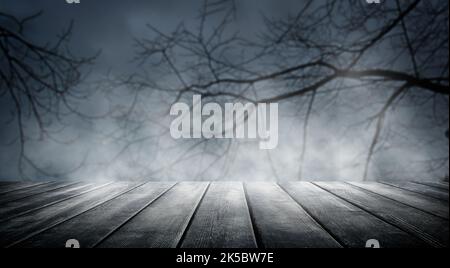 Spooky misty horror Halloween background with empty wooden planks, for product placement. Old wooden table and dead tree silhouette at night for Hallo Stock Photo