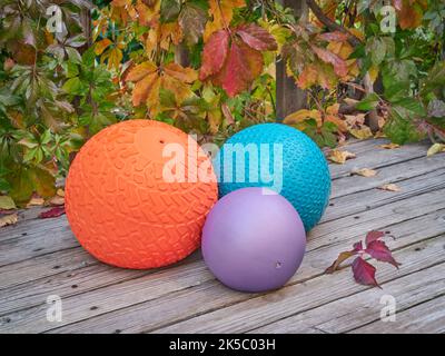 three heavy slam balls filled with sand on a backyard deck with fall vine foliage, exercise and functional fitness concept Stock Photo