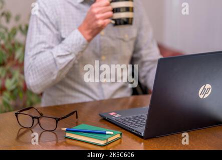 Man sitting at a desk typing on a laptop Stock Photo