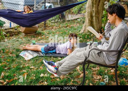 A father reads a book to his children outside in backyard Stock Photo