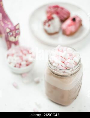 Close-up of a hot drink and mini marshmallows on a white table and in the background Traditional French dessert eclairs Stock Photo