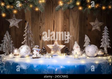 Christmas ornaments, lights and snow on blue surface and wooden background with copy space Stock Photo