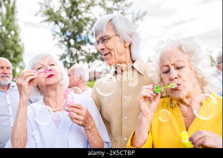 Group of happy elderly people bonding outdoors at the park - Old people in the age of 60, 70, 80 having fun and spending time together, concepts about Stock Photo