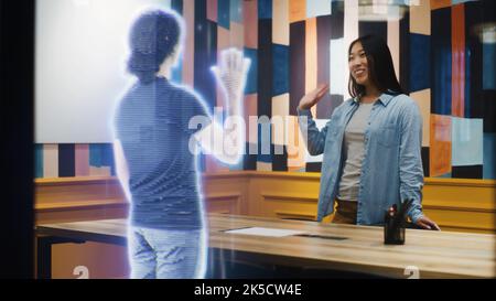 Asian woman talks on the call with her friend using augmented reality software. Hologram of her friend appears infront of her receiving the call. VFX special effects. Futuristic technology concept. Stock Photo
