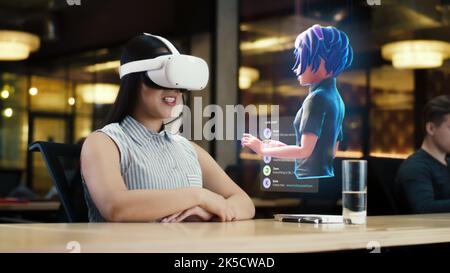 Young asian woman wearing VR headset conversing with a cartoon character avatar via an futuristic screen hologram. Futuristic communication scifi concept. 3D rendering picture. Augmented reality. Stock Photo