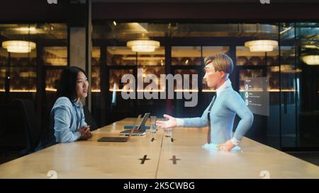 Video call chat conference of an asian woman using hologram technology. Conversing with a cartoon character avatar of young man. Advanced technology. VFX. Augmented reality. Stock Photo