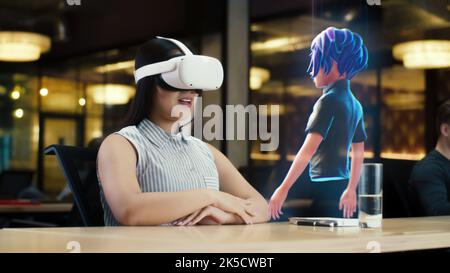 Young asian woman wearing VR headset conversing with a cartoon character avatar via an futuristic screen hologram. Futuristic communication scifi concept. 3D rendering picture. Augmented reality. Stock Photo