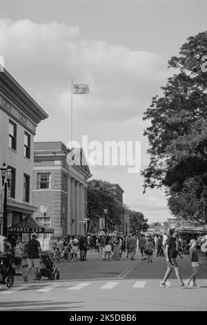 Crowds of visitors walk the streets at at the Lowell Folk Festival in historic Lowell, Massachusetts. The image was captured on black and white analog Stock Photo