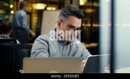 Male office worker, using tablet computer and digital pencil, working in modern office on startup project, business strategy or design of website. Work in IT company Stock Photo