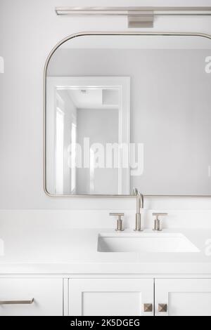A bathroom detail shot with a white cabinet, bronze mirror and faucet, and marble countertop. Stock Photo